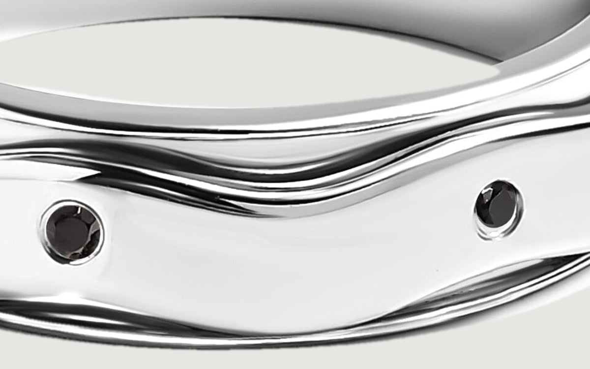 A close view shows round black stones set into the broad reflective silver band.
