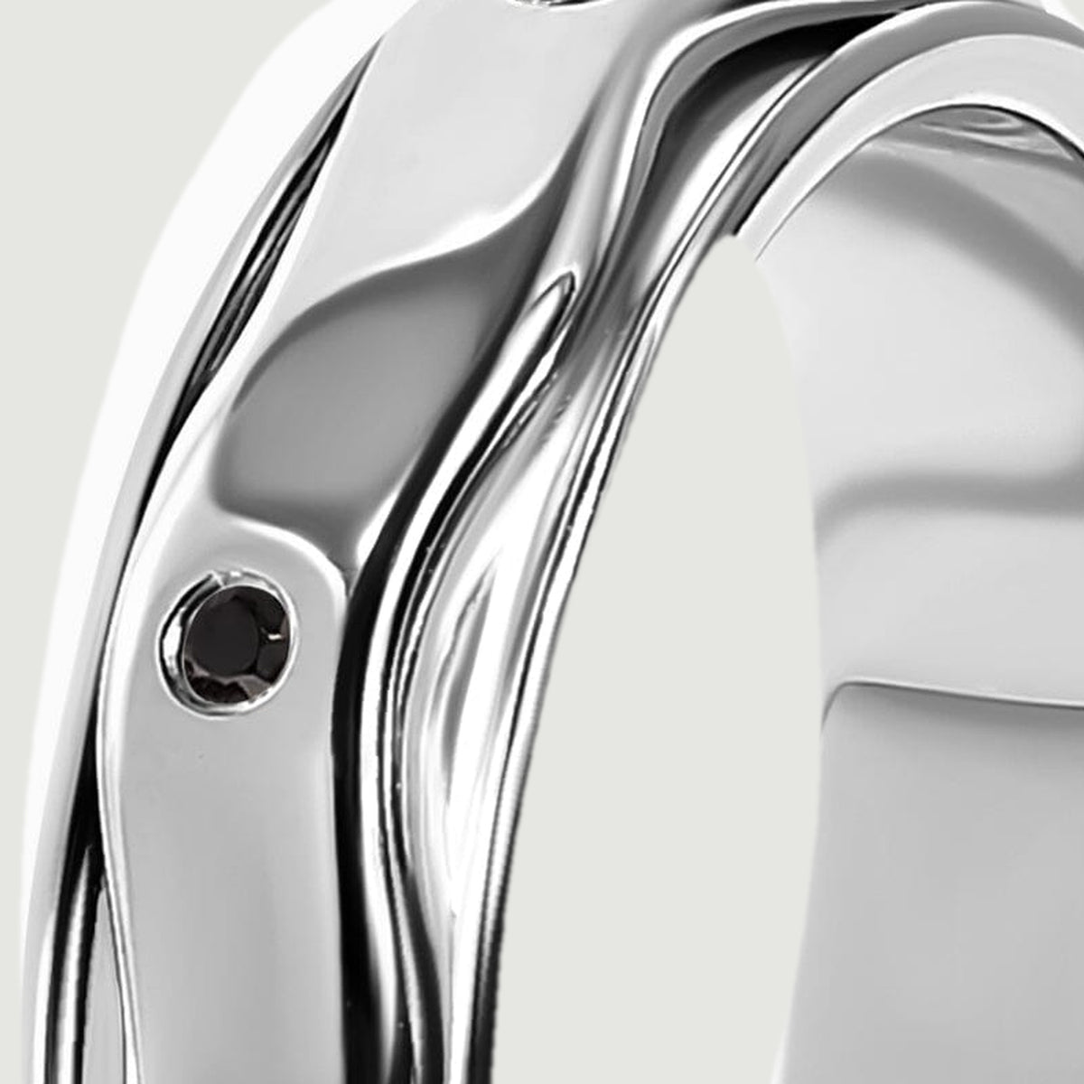 Polished silver rails follow the curved edge of the ring beside a small black stone.