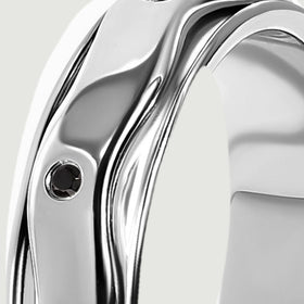Polished silver rails follow the curved edge of the ring beside a small black stone.