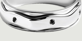 The turned outer band displays black stones beneath an undulating polished silver edge.