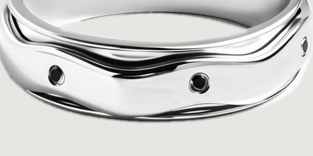 The turned outer band displays black stones beneath an undulating polished silver edge.
