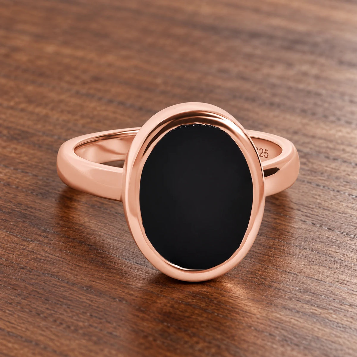 Stillpoint black onyx oval ring in rose gold vermeil, complete front view on walnut.