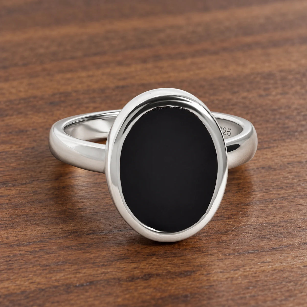 Stillpoint black onyx oval ring in sterling silver, complete front view on walnut.
