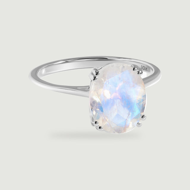 An oval moonstone with a blue sheen sits in paired prongs on a polished white gold ring.