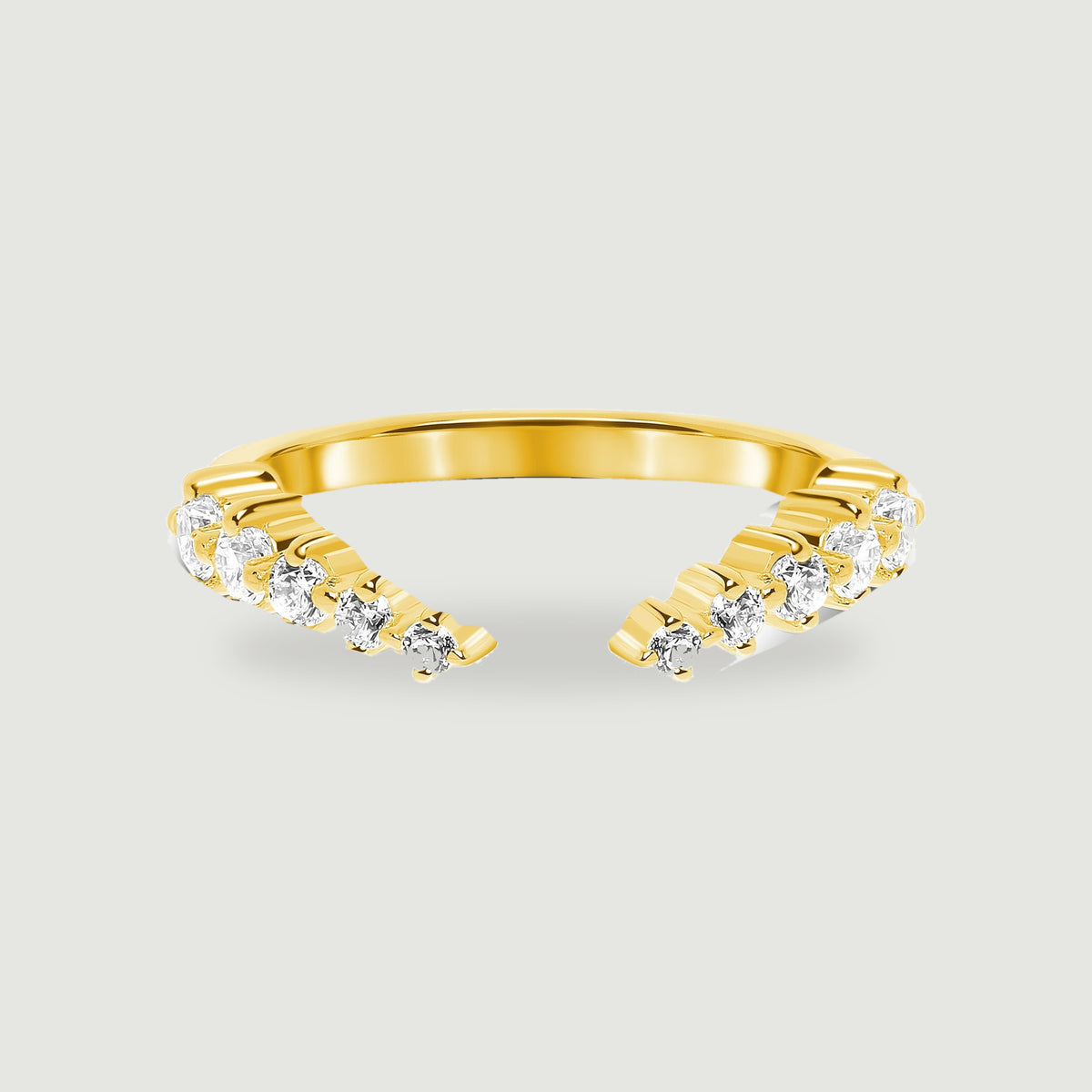 A yellow gold vermeil band has clear round stones along its two open ends against light gray.