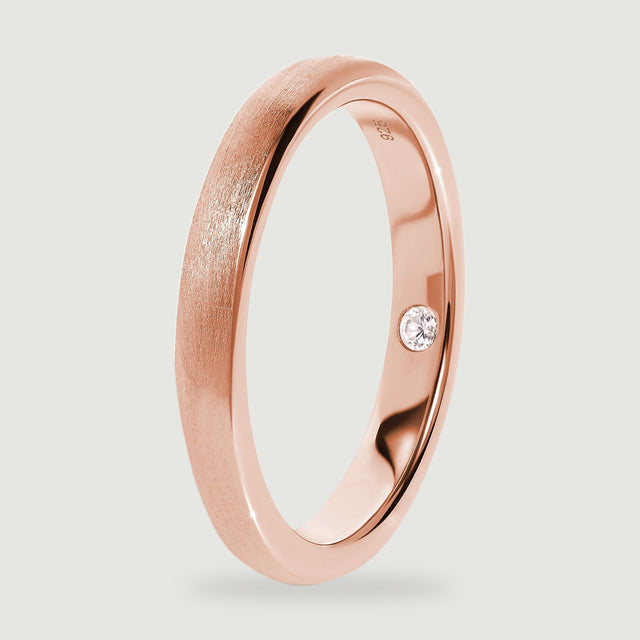 The side view of a rose gold ring shows its brushed outside and reflective inner surface.