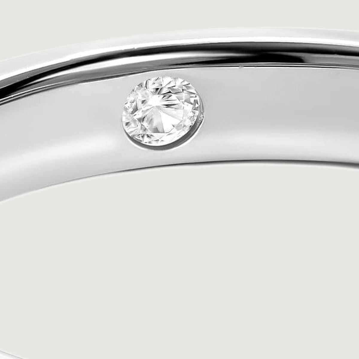 A close view shows a round faceted clear stone set inside the polished silver band.