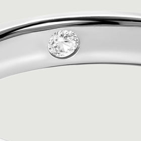 A close view shows a round faceted clear stone set inside the polished silver band.