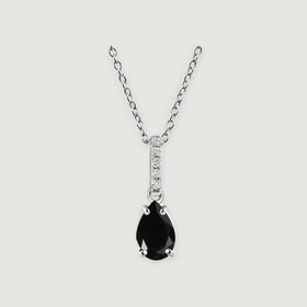 A sterling silver chain holds a pear-shaped black onyx pendant beneath a row of clear stones on a pale gray background.