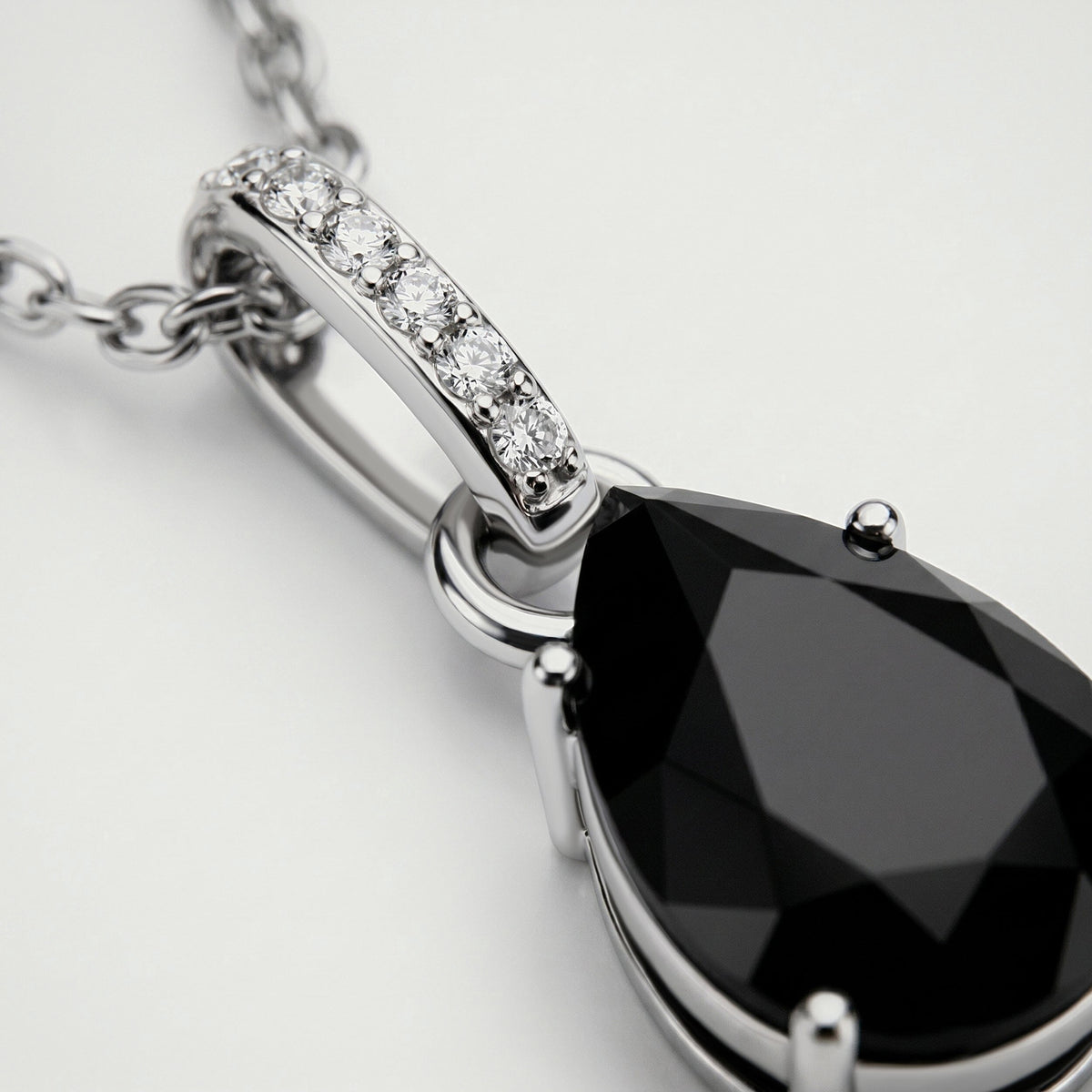 A close view reveals the silver prongs, dark onyx facets, and round clear stones along the pendant bail.