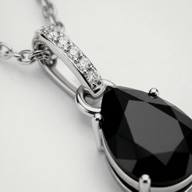 A close view reveals the silver prongs, dark onyx facets, and round clear stones along the pendant bail.