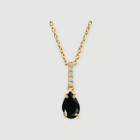 A yellow gold vermeil chain and four-prong black onyx pendant are centered against a light gray surface.