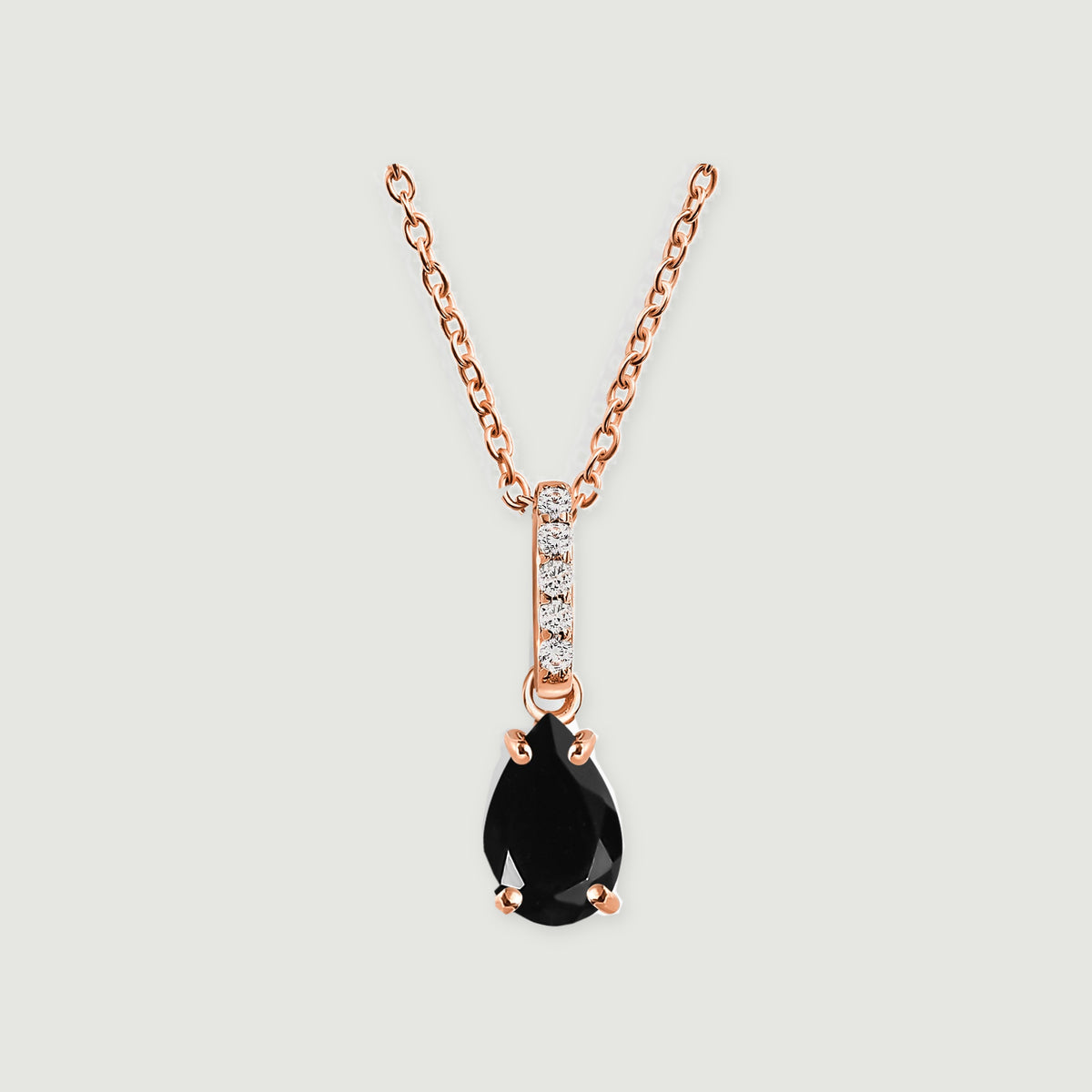 A rose gold vermeil necklace displays a glossy black teardrop stone and a narrow clear-stone bail on pale gray.
