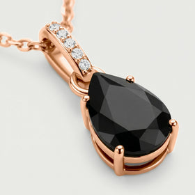 Rose gold vermeil prongs surround the black onyx stone beneath five clear stones in a close pendant view.