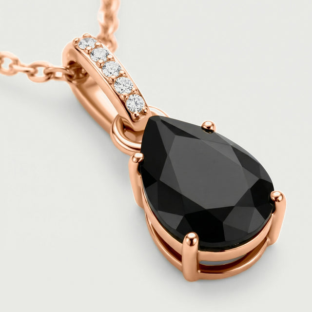 Rose gold vermeil prongs surround the black onyx stone beneath five clear stones in a close pendant view.