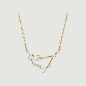 A yellow gold necklace with four pale iridescent stones and smaller clear stones rests against a light gray background.