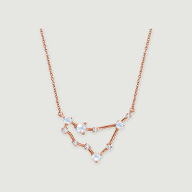 A rose gold necklace shows a fine chain and an angular arrangement of round stones on a light gray surface.