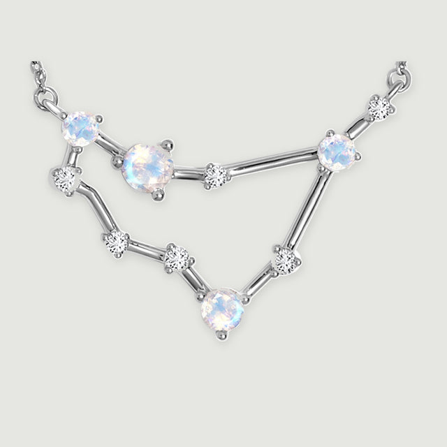The silver necklace centerpiece displays reflective round stones, fine prongs, and slender connecting bars.