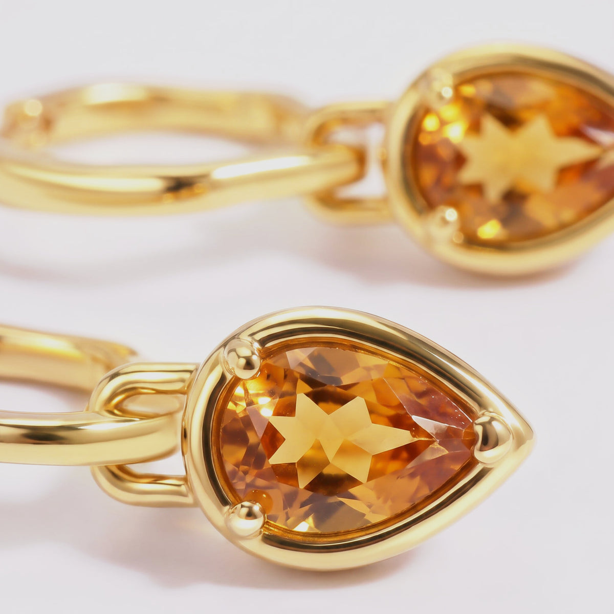 A close view shows the golden citrine facets and rounded prongs of a yellow gold plated drop.