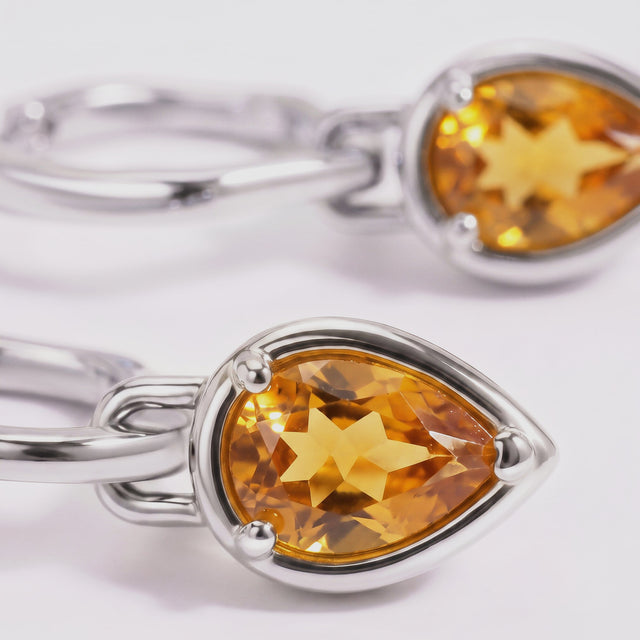 Faceted amber citrine and the polished white rhodium plated setting fill this close-up.