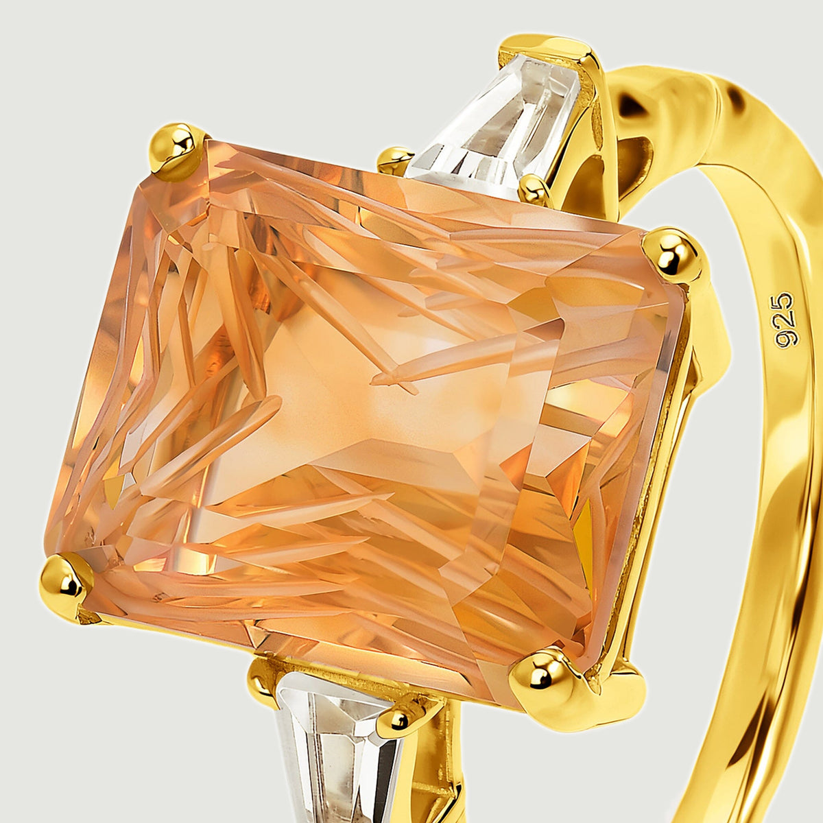 An angled close view reveals the carved citrine facets, gold corner prongs, and clear tapered side stones.