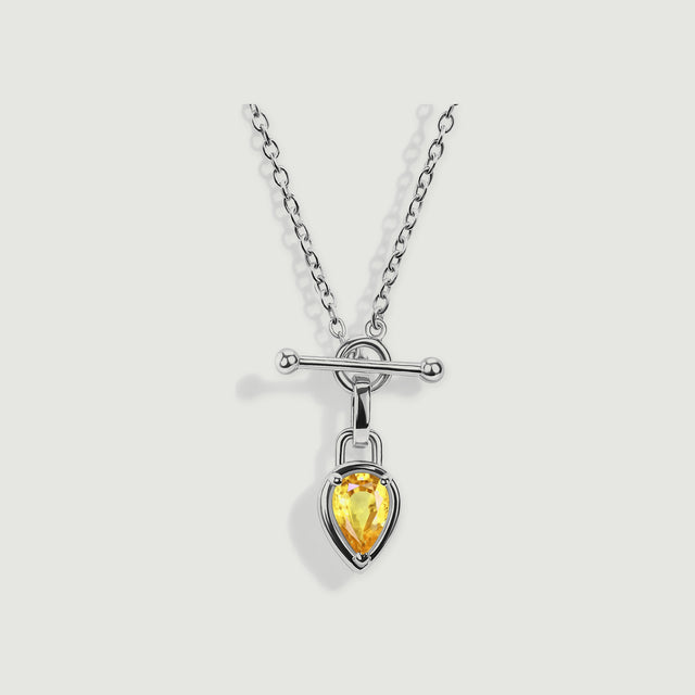 A white rhodium plated necklace displays a yellow pear shaped stone beneath a circular clasp and rounded bar.