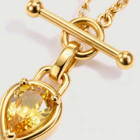 A close view shows the gold toned bar, circular clasp and faceted yellow stone.
