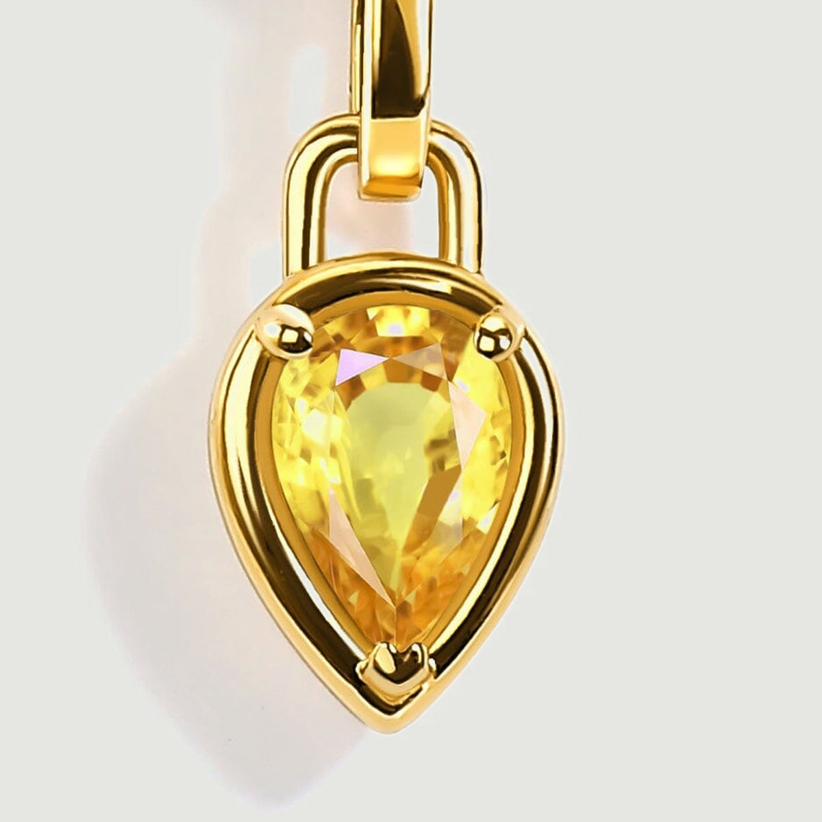Three rounded gold toned prongs frame the pear shaped yellow gemstone beneath a polished curved bail.