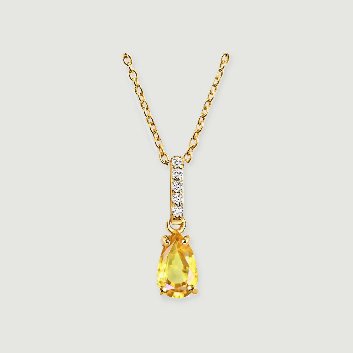 A yellow gold necklace has a pear-shaped yellow gemstone below a straight row of five clear stones.