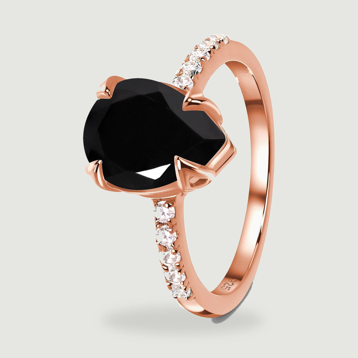 A rose gold vermeil ring stands at an angle, showing its black faceted stone, open setting and clear shoulder stones.
