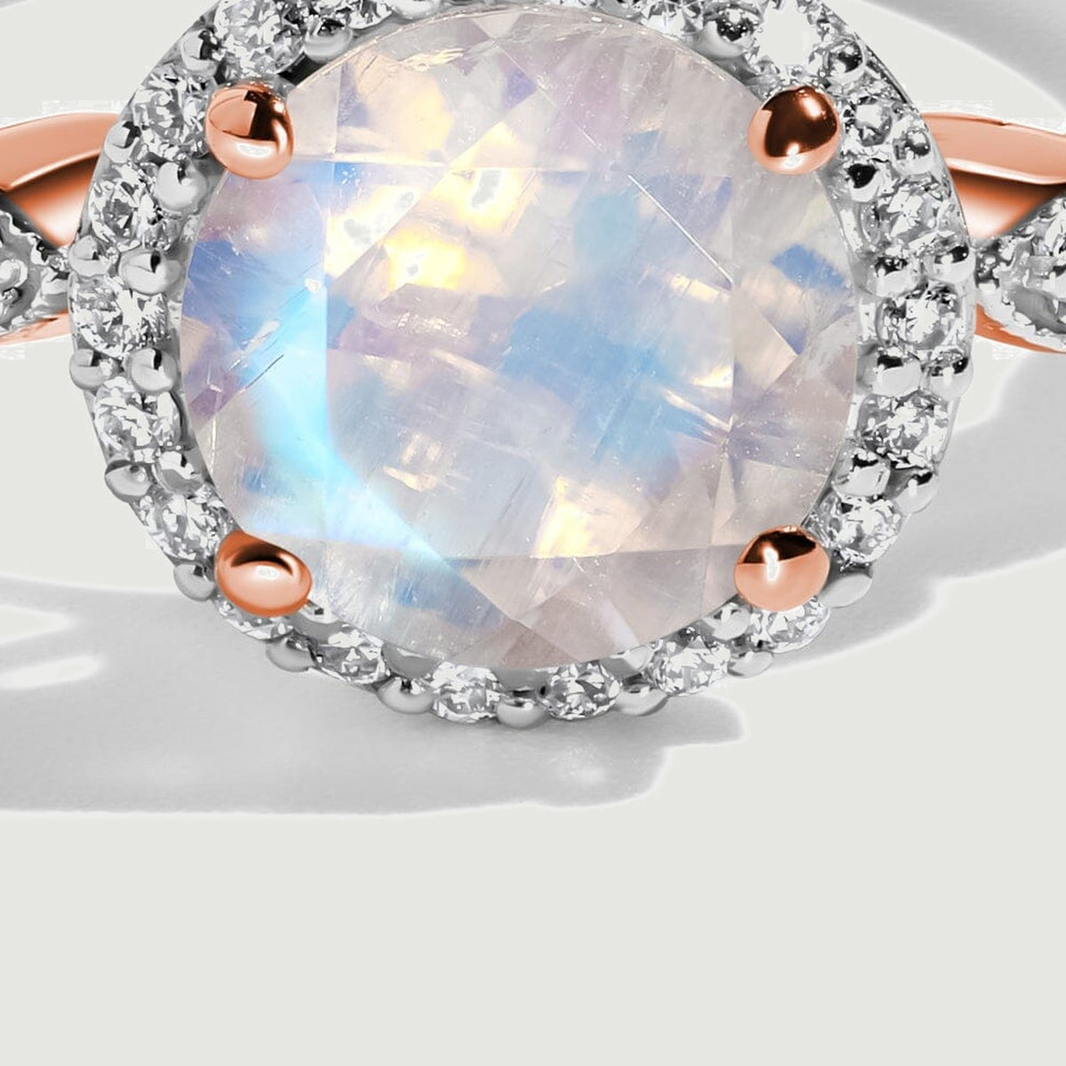 The rose gold prongs and scalloped shoulders are visible beside the faceted moonstone in this close view.