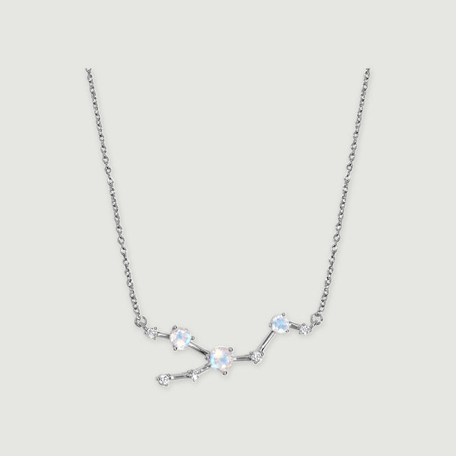 A silver necklace displays an asymmetric arrangement of round iridescent stones and small clear accents.