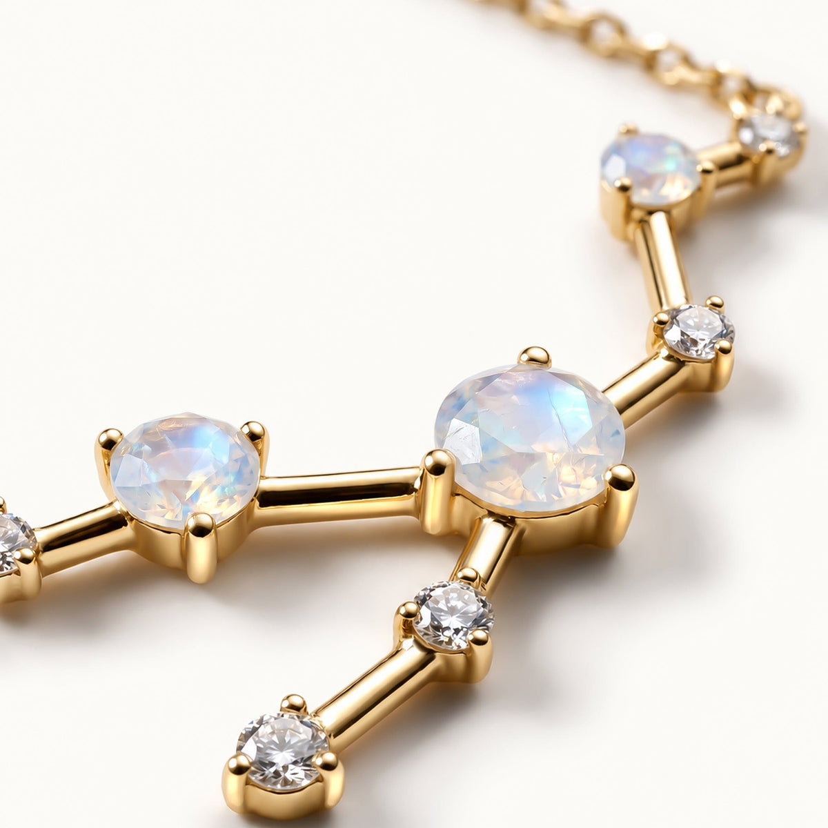 Faceted pale stones and small clear stones sit in polished yellow gold prong settings.