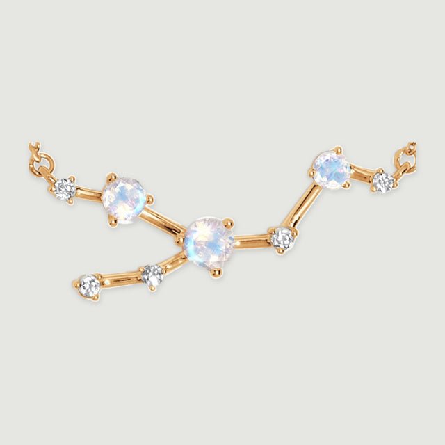 Three iridescent stones and five clear accents form a branching yellow gold centerpiece on a light gray surface.