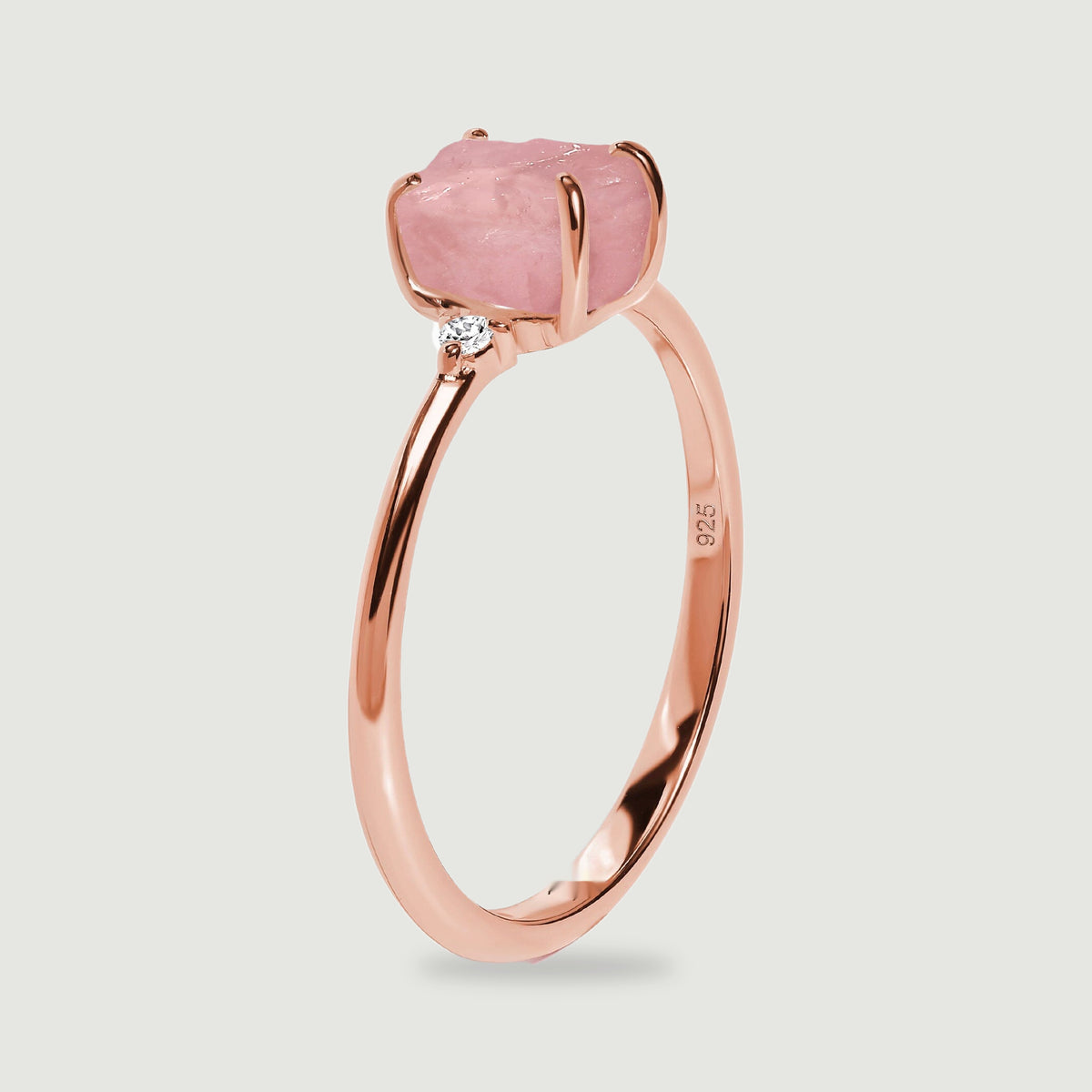 The upright rose gold ring shows its raised pink stone, curved prongs, and narrow band from the side.