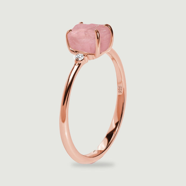 The upright rose gold ring shows its raised pink stone, curved prongs, and narrow band from the side.