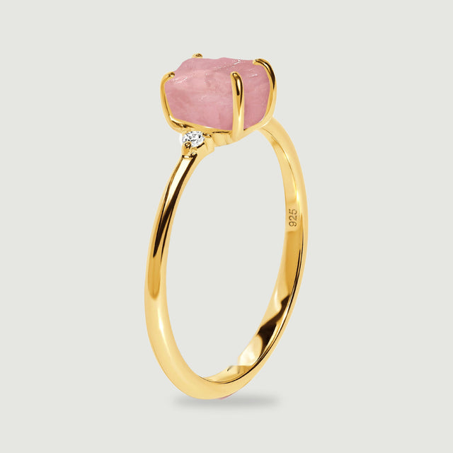 The upright yellow gold ring shows its raised pink stone, curved prongs, and narrow band from the side.