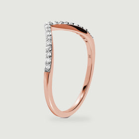A rose gold ring stands on its edge, showing the curved shank and diamond-lined front.