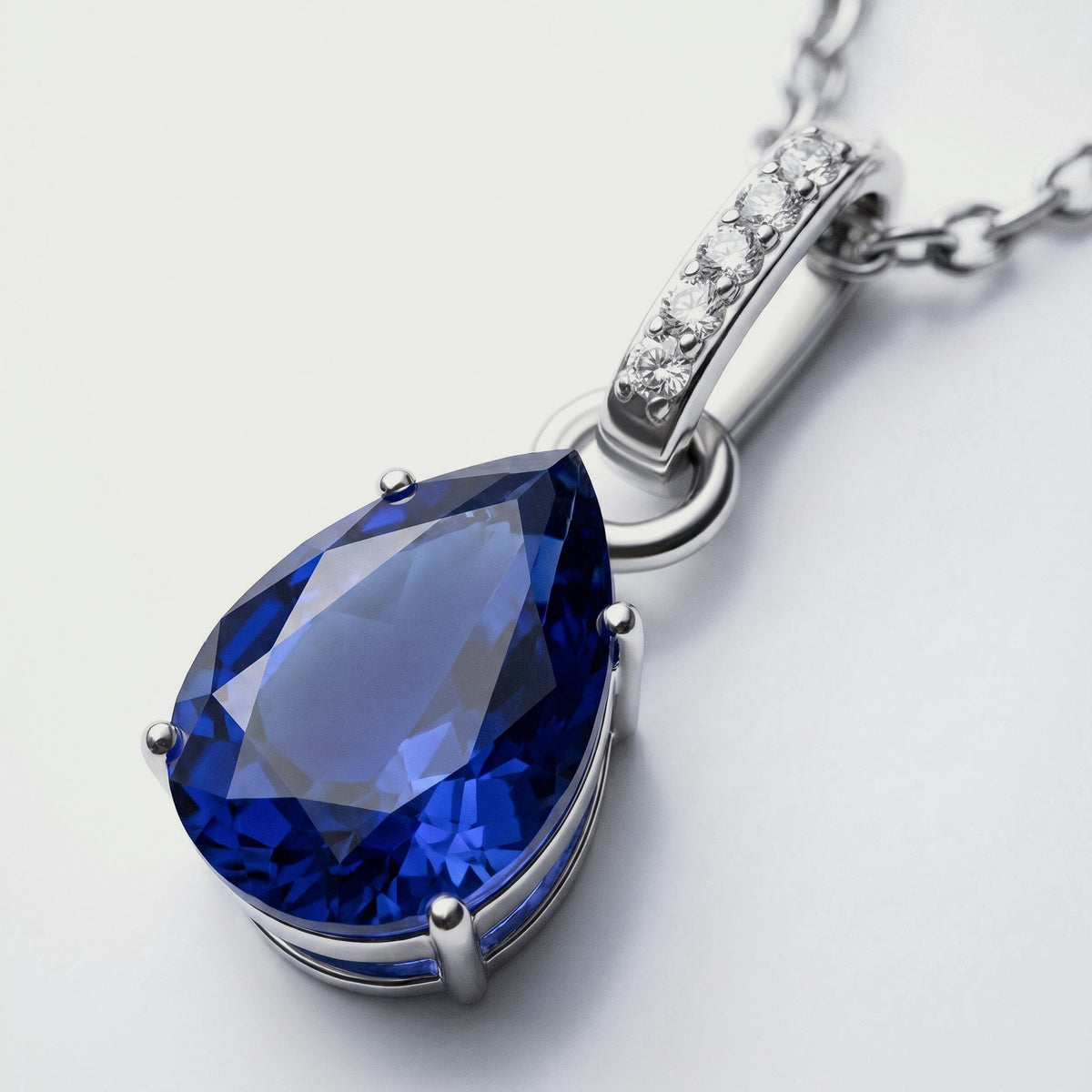 A silver prong setting surrounds the blue sapphire while five round clear stones line the elongated bail.