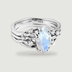A sterling silver ring shows a blue flashing marquise moonstone framed by polished curves and clear round stones.