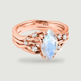 A rose gold vermeil ring displays a pointed moonstone above curved bands with scattered clear accents.