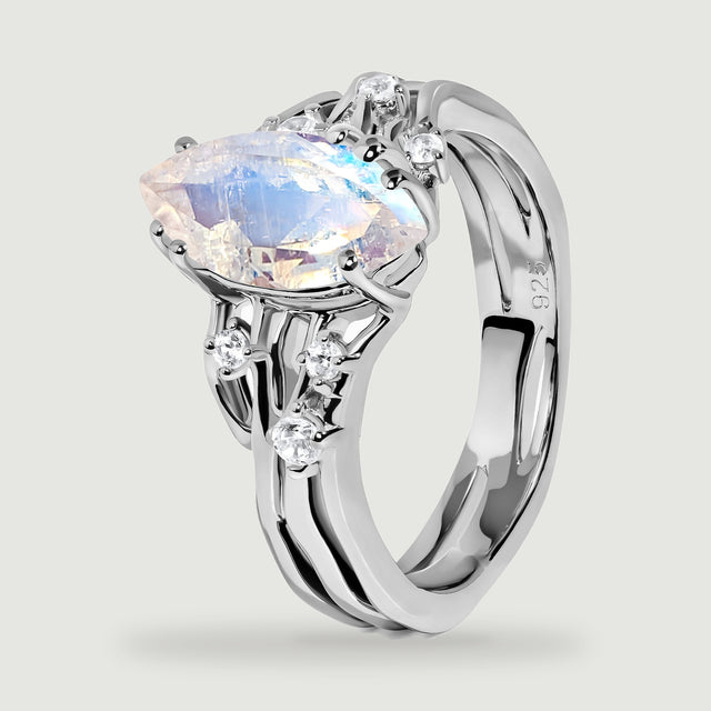 The side of a sterling silver ring reveals the faceted moonstone, clear accent stones, and a polished inner band.