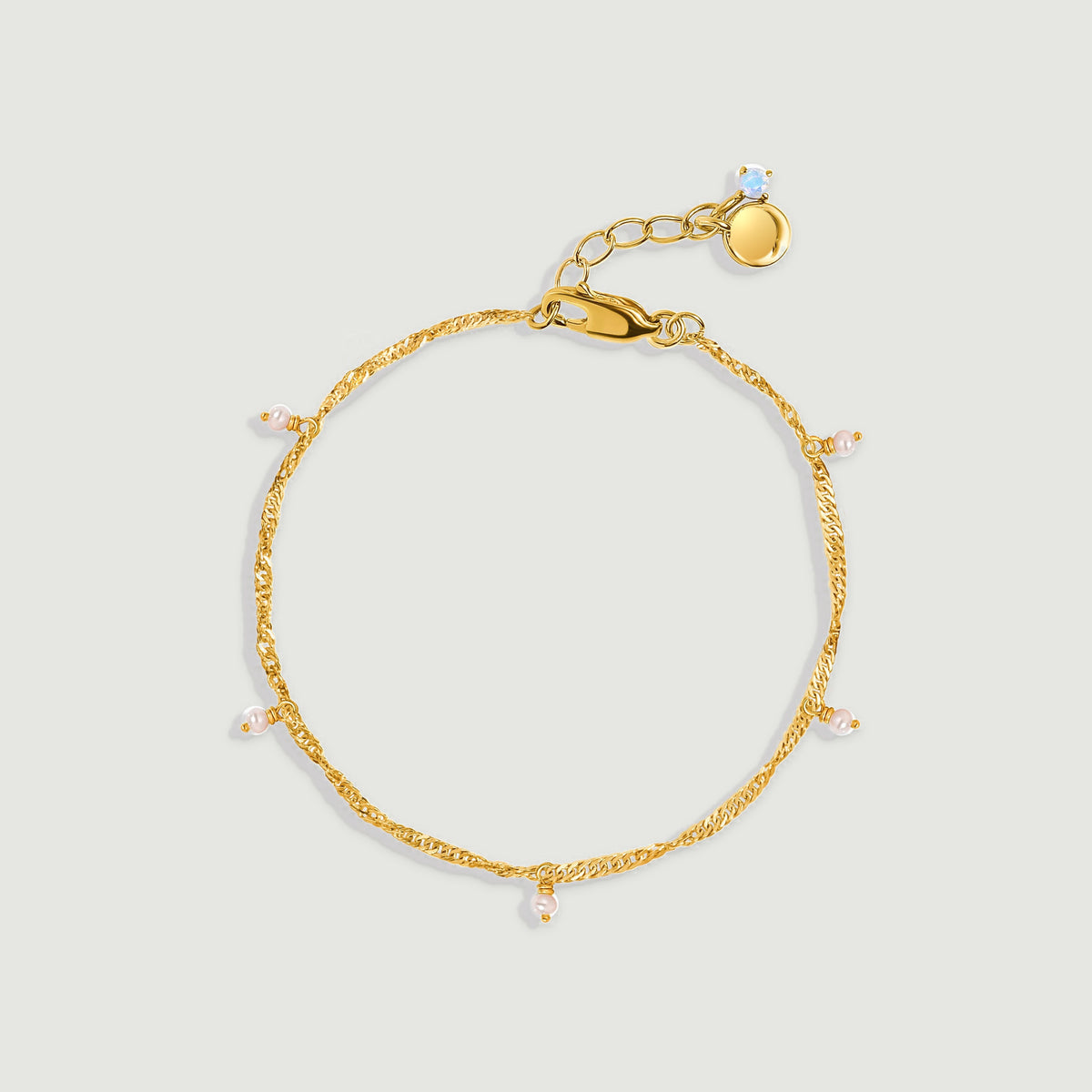 A yellow gold anklet with five small pearl drops and an extender is arranged on a light gray background.