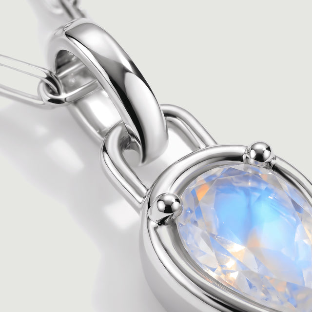 A close-up shows the polished silver-tone bail, rounded prongs, and blue reflections inside the moonstone.