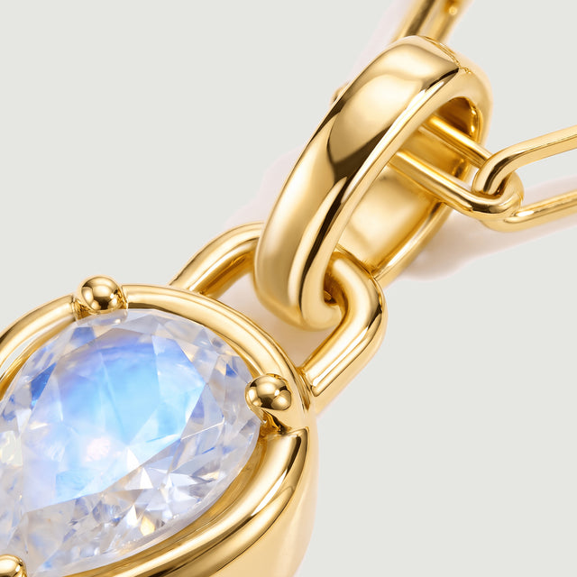 The gold-tone pendant connector and rounded stone setting fill the frame beside pale blue moonstone facets.