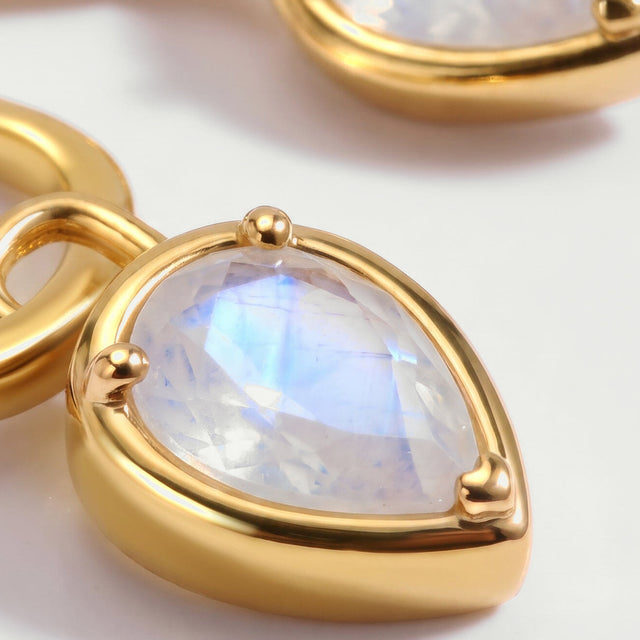 The faceted pear-shaped moonstone is shown close up in a glossy yellow-gold-tone setting.