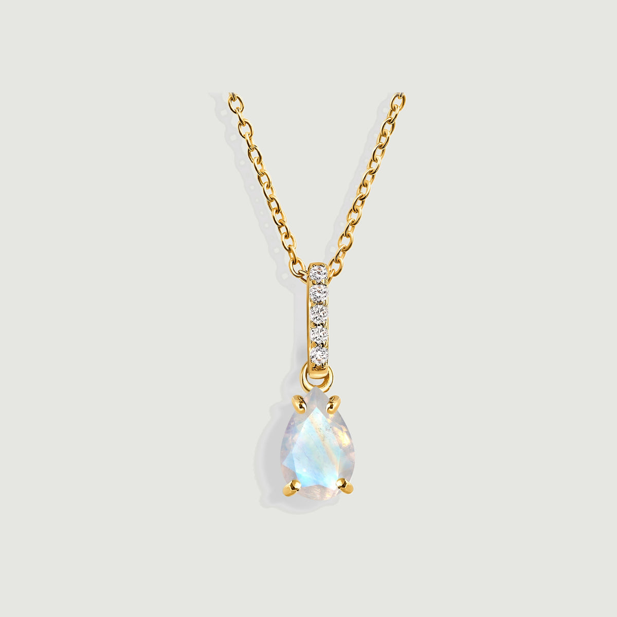 A yellow gold vermeil necklace displays a faceted pear-shaped moonstone and a vertical row of five diamonds on light gray.