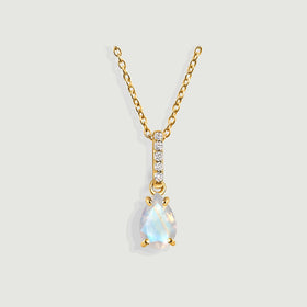 A yellow gold vermeil necklace displays a faceted pear-shaped moonstone and a vertical row of five diamonds on light gray.