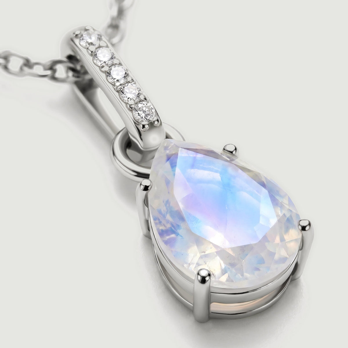 A close view shows the blue sheen of the moonstone, rounded silver prongs, and five diamonds along the bail.