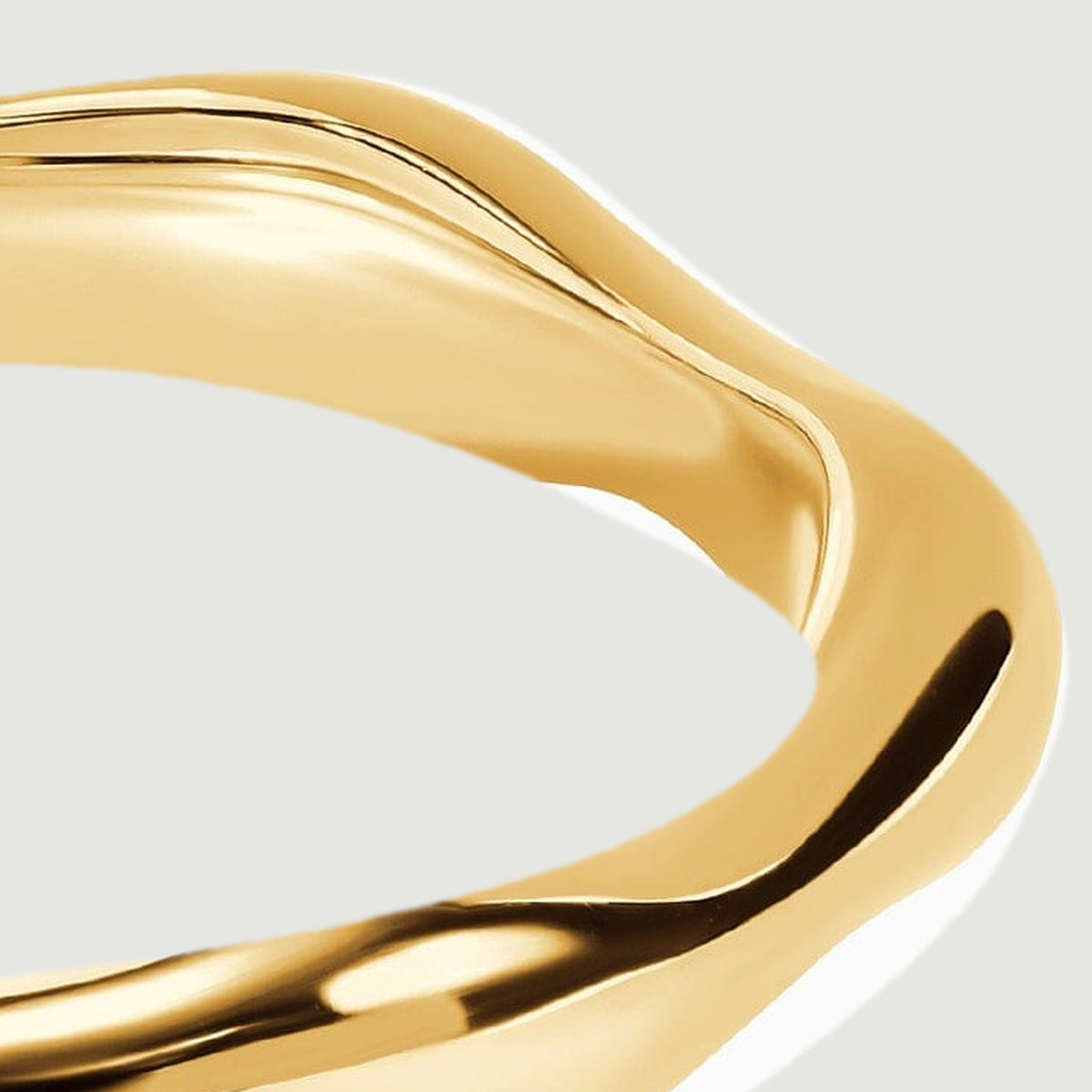 A close view of the yellow gold band reveals its rounded shoulder and reflective curved rim.